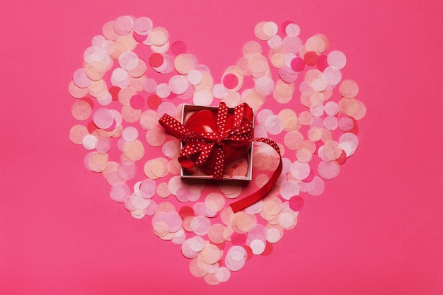 Kształt serca wykonany z różowego brokatu z prezentem. Leżał płasko. Koncepcja miłości.
