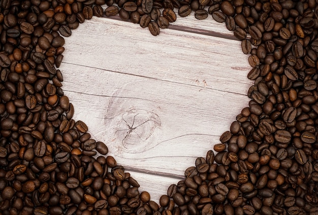 Kształt serca z palonych ziaren kawy na drewnianym stole