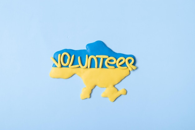 Kształt ukraiński w kolorze żółtoniebieskim i napis wolontariusz na niebieskim tle widok z góry