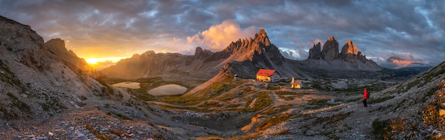 Kształtuje teren panorama widok dom i góra z złocistym niebem na zmierzchu od Tre Cime, dolomity, Włochy.