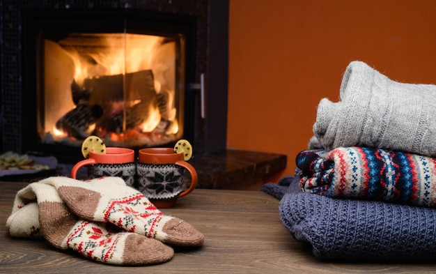 Kubek gorącego napoju przed ciepłym kominkiem Stos przytulnych swetrów z dzianiny