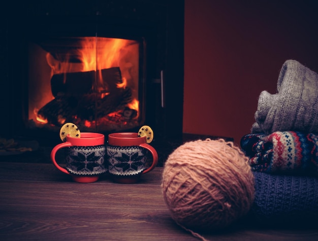 Zdjęcie kubek gorącego napoju przed ciepłym kominkiem stos przytulnych swetrów z dzianiny