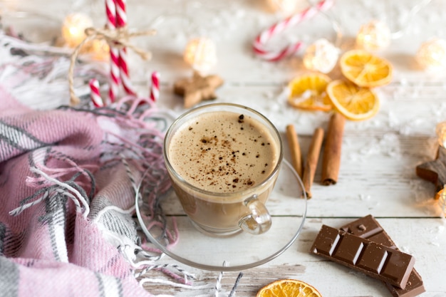Kubek gorącej cappuccino lub gorącej czekolady mlecznej z suszonymi owocami pomarańczy i cynamonem.