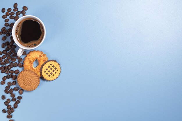 Kubek gorącej kawy i różne ciasteczka na niebieskim tle, widok z góry. Miejsce na tekst