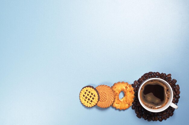 Kubek gorącej kawy i różne słodkie ciasteczka na niebieskim widoku z góry Miejsce na tekst