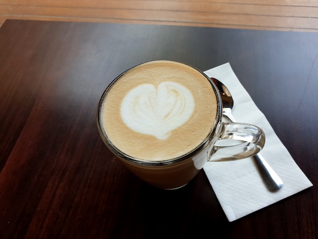 Kubek gorącej kawy latte art na drewnianym stole
