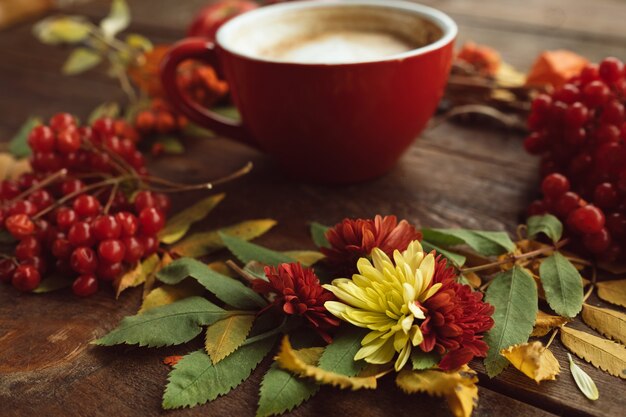 Kubek gorącej latte na ścianie jesieni. Bukiet upadku na drewnianej szorstkiej powierzchni.