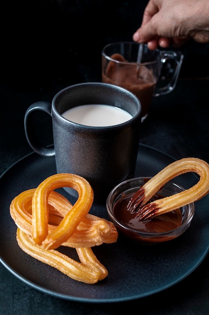 Kubek gorącej mlecznej ciemnej czekolady i talerz ze świeżymi churros