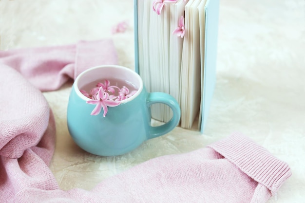 Kubek z napojem zakładki do książek ze świeżych kwiatów w wełniany różowy sweter z otwartą książką