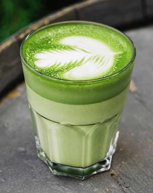 Kubek z pianki mlecznej Matcha latte w kolorze zielonym na drewnianej beczce