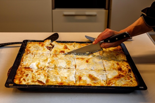 Kucharz kroi świeżą lasagne z boku