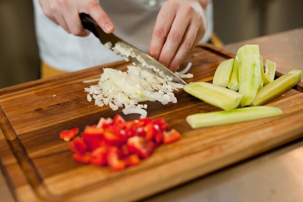 Kucharz kroi warzywa nożem, aby przygotować potrawę Krojenie warzyw