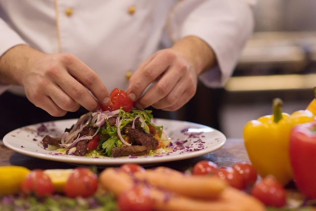 kucharz kucharz dekorujący przybranie przygotowane danie na talerzu w komercyjnej kuchni restauracji