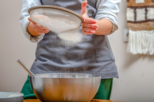 Zdjęcie kucharz przesiewa mąkę przez sito, aby zrobić ciasto