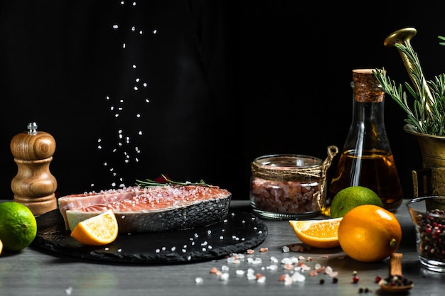 Kucharz przygotowuje stek z łososia posypującego solą morską w zamrożonym ruchu o miejsce przepisu na czarny baner menu na tekst