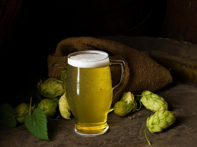Zdjęcie kufel piwa kłosy pszenicy chmielu i beczka piwa na podłoże drewniane