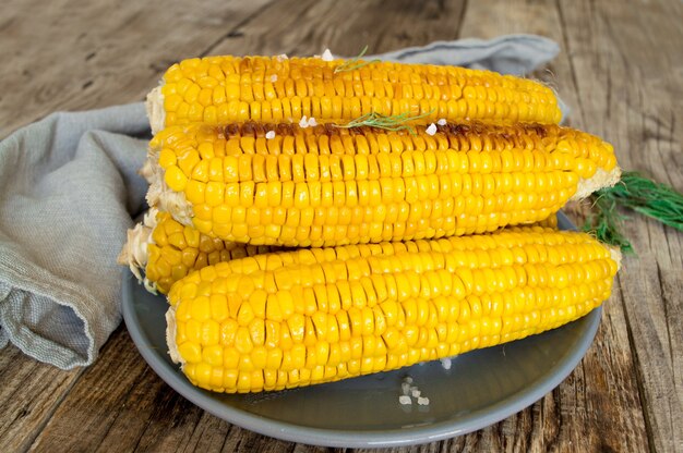 Kukurydza grillowana, kukurydza gotowana na drewnianym białym talerzu. Jedzenie wegetariańskie, zdrowa żywność.