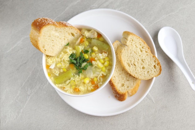 Kukurydza i szparagi z zupą jajeczną w białej misce i chrupiącym pieczywem