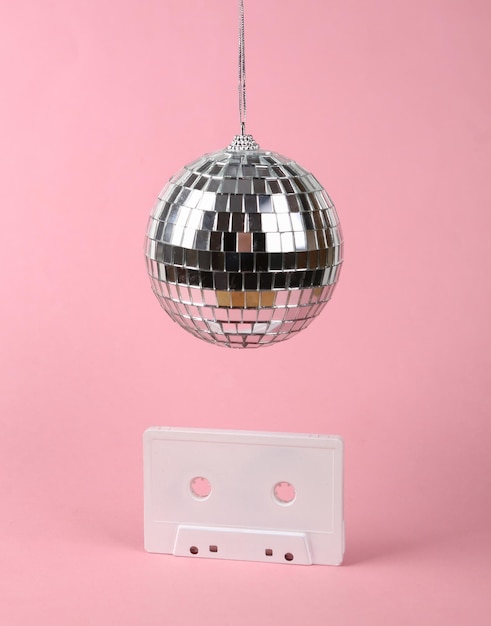 Kula dyskotekowa z retro kasetą audio na różowym tle Koncepcja partii minimalizmu