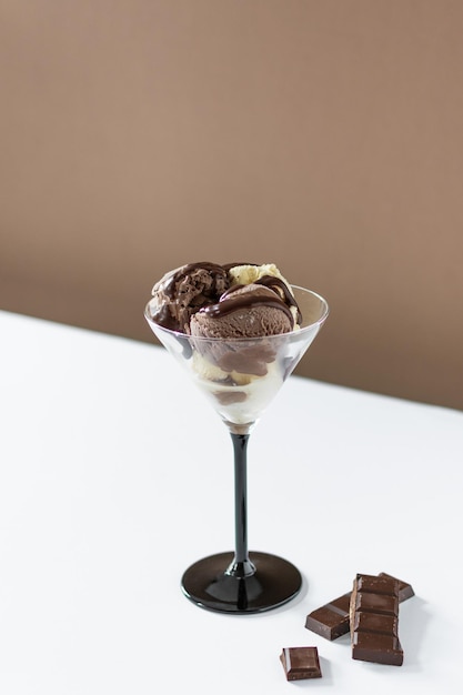 Kulki lodów czekoladowych w szklance na nowoczesnym brązowym i białym tle