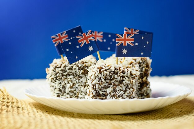 Kultowe tradycyjne australijskie przyjęcie, ciasta Lamington na czerwonym, białym i niebieskim tle. Flaga Australii.