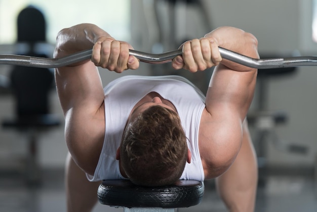 Zdjęcie kulturysta ćwiczący triceps ze sztangą na siłowni