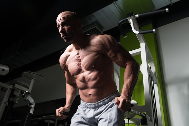 Kulturysta fitness mięśni wykonujący ćwiczenia z dużymi ciężarami na triceps i klatkę piersiową na poręczach na siłowni