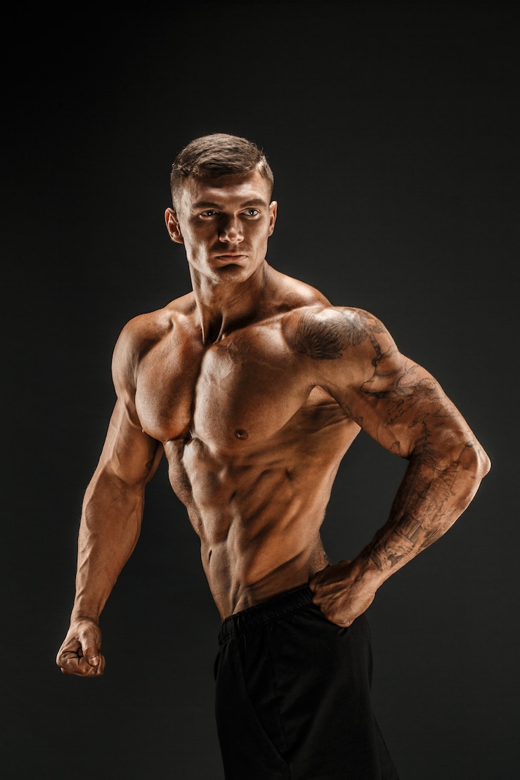 Zdjęcie kulturysta pozowanie fitness umięśniony mężczyzna na ciemnej scenie