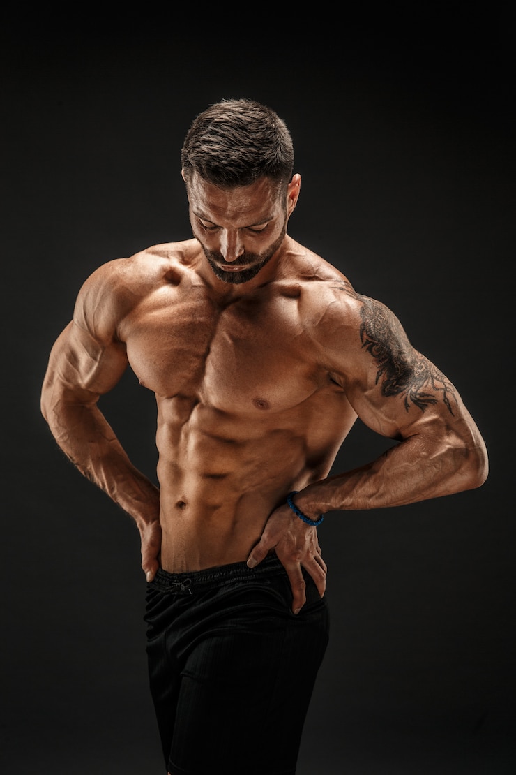 Zdjęcie kulturysta pozowanie. fitness umięśniony mężczyzna na ciemnej ścianie.