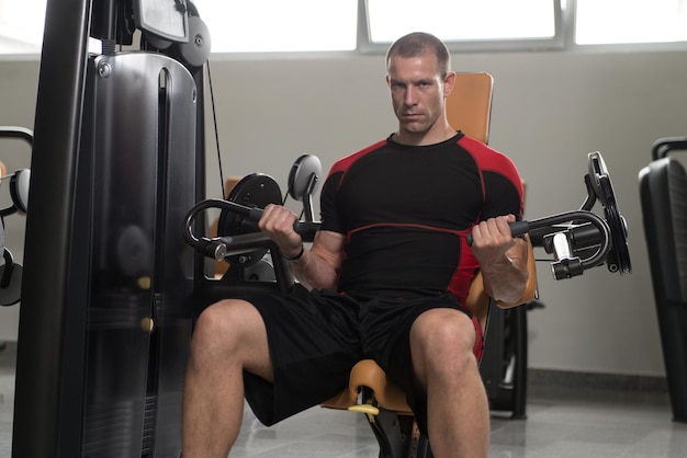 Kulturysta wykonujący ćwiczenia na biceps na maszynie