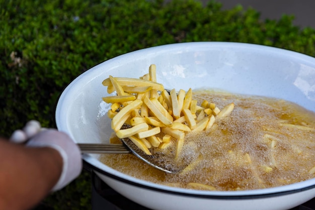 Kupie frytki w misce frytkownicy z wrzącym olejem