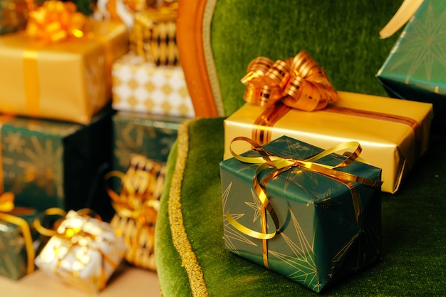 Kupie owinięte zielone i złote prezenty na Boże Narodzenie