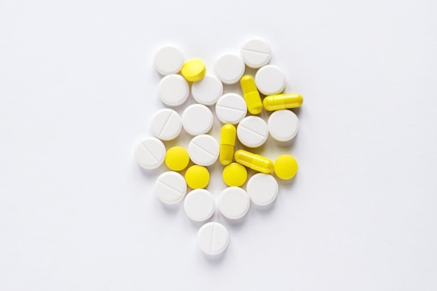 Kupie żółte i białe tabletki na białej powierzchni.