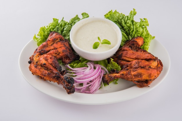 Kurczak Tandoori - Przygotowywany Przez Pieczenie Kurczaka Marynowanego W Jogurcie I Przyprawach W Piecu Tandoor. Kawałek Nogi Podawany W Talerzu Z Sałatką Na Kolorowym Lub Drewnianym Tle. Selektywne Skupienie