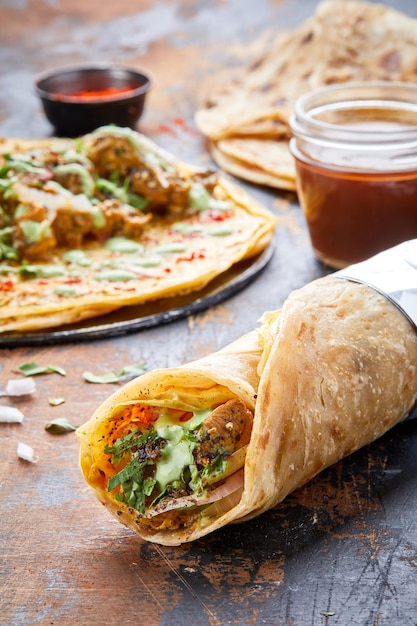 Kurczak z czarnego pieprzu paratha roll kathi shawarma wrap z sosem zanurzeniowym na białym tle na tle bocznego widoku indyjskiego fastfoodu