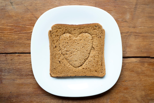 Kwadratowy grillowany tost z wytłoczonym symbolem serca na białym talerzu