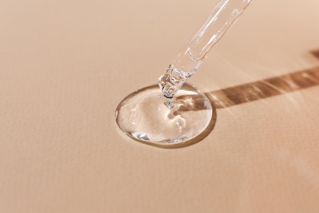 Kwas hialuronowy w szklanej pipecie na beżowym tle transparentne serum o pięknej konsystencji