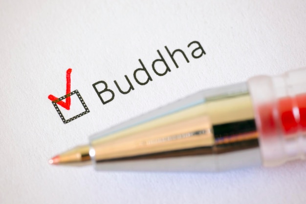 Zdjęcie kwestionariusz czerwony długopis i napis buddhist ze znacznikiem wyboru na białej księdze