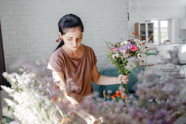 Zdjęcie kwiaciarnia brunetki z europy robi bukiet kwiatów i ziół w swoim warsztacie