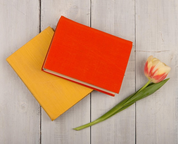 Kwiatowy tulipan i kolorowe książki na białym drewnianym stole
