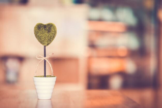 Kwiatu garnek z zielonym sercem na drewnianym stole z bokeh i kopii przestrzenią