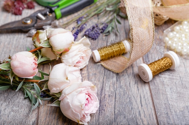 Kwiaty narzędzia wstążki róże lawenda zioła zielenie na stole kwiaciarni w kwiaciarni Drewniany stół w stylu rustykalnym miejsce pracy