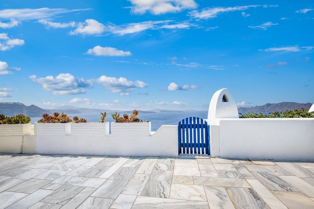 Kwiaty, niebieskie drzwi. Biała architektura Wyspa Santorini, Grecja. Piękny krajobraz z widokiem na morze