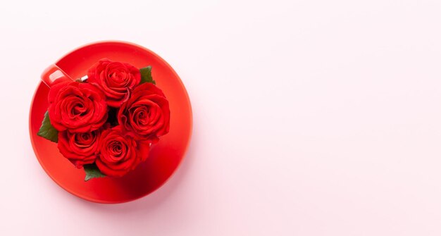 Kwiaty róży w filiżance do kawy i płatkach Karta powitalna na Dzień Świętego Walentynki z miejscem na twoje pozdrowienia