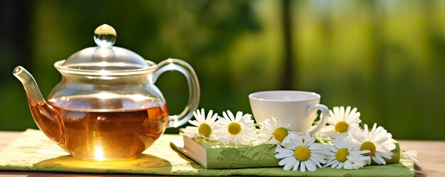Zdjęcie kwiaty rumianku książki szklany czajnik i filiżanka herbaty ziołowej na stole zbliżenie generatywna sztuczna inteligencja