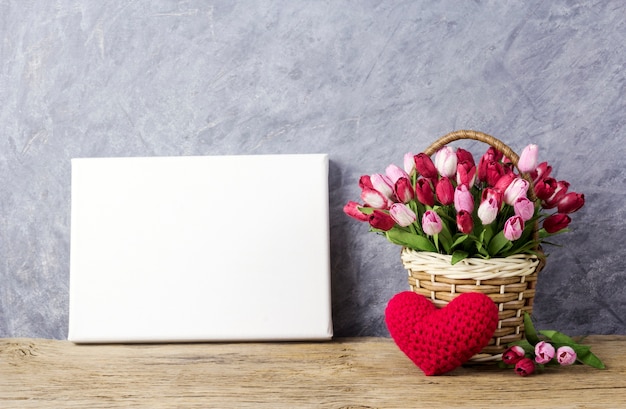 Kwiaty tulipanów w drewniane pudełko z czerwonym sercem i puste płótno ramki