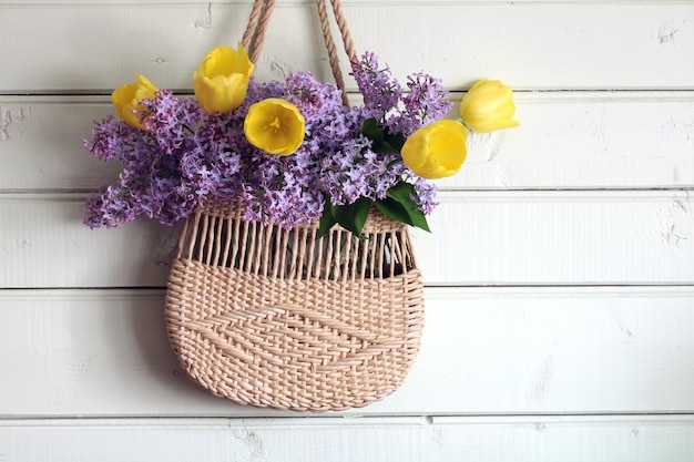 Zdjęcie kwiecisty tło z bzami i tulipanami w plecionej torbie