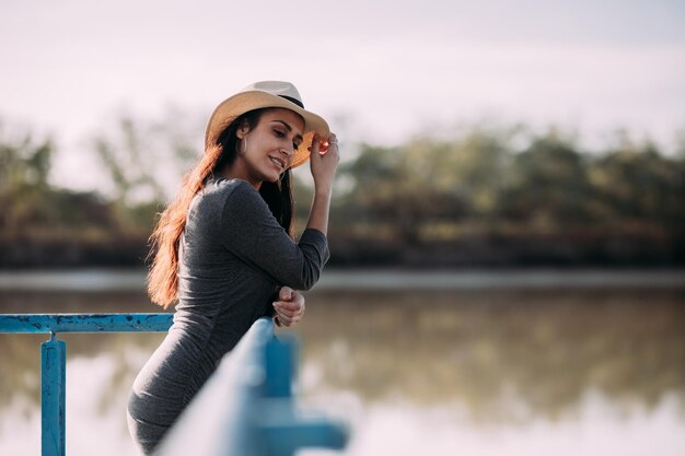 Łacińska brunetka w kapeluszu relaksuje się w doku nad rzeką Pojęcie odłączenia w przyrodzie