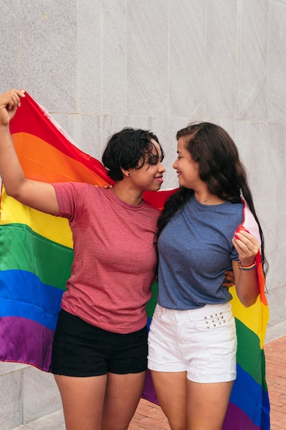 Łacińska para lesbijek z flagą LGTB w mieście. Koncepcja LGBT