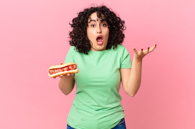 Ładna arabska kobieta czuje się bardzo zszokowana i zaskoczona i trzyma hot doga